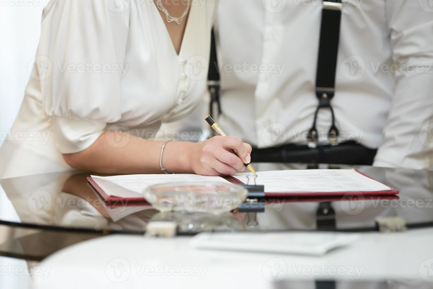 el novia y novio firmar en el registro oficina, firmar el matrimonio contrato. foto