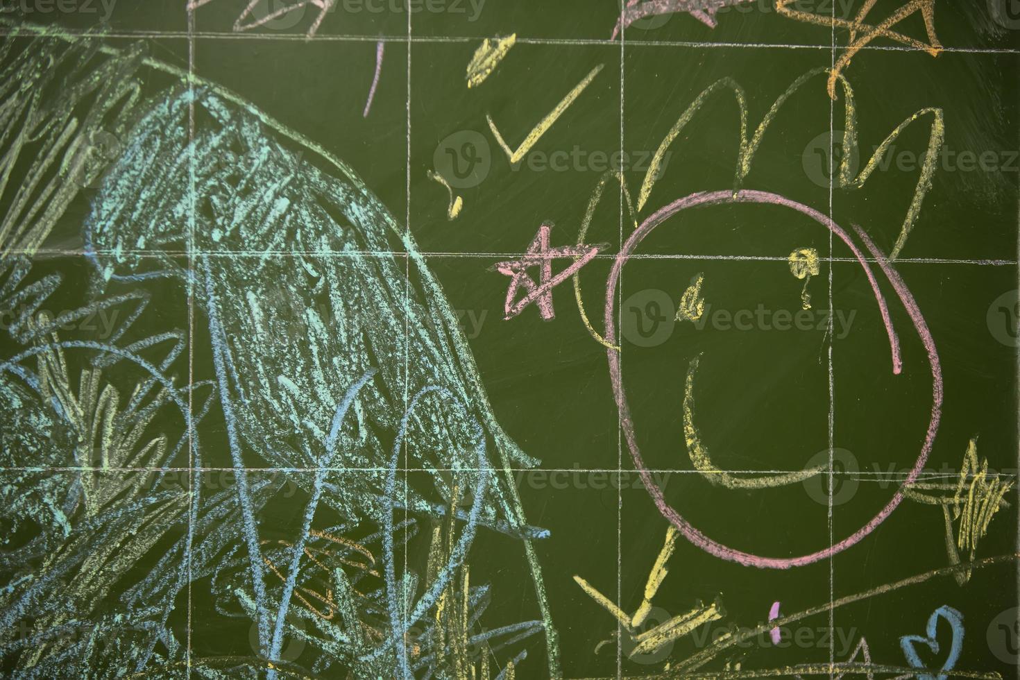 Drawings of children with chalk on a school green board. photo