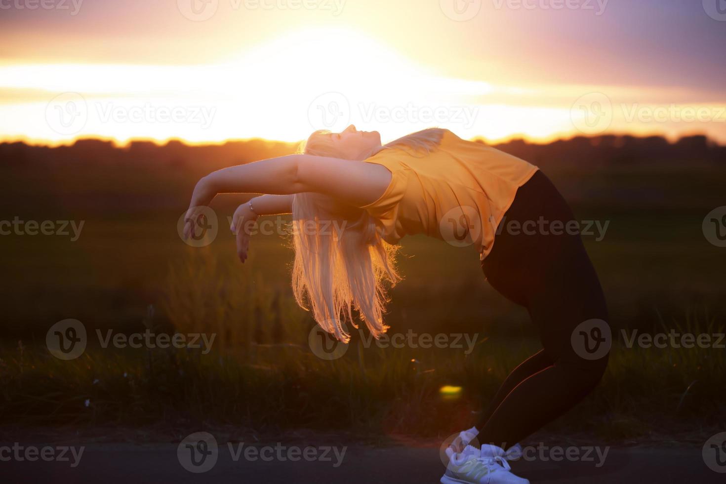 A plump woman in a tracksuit goes in for sports against the sunset sky. photo