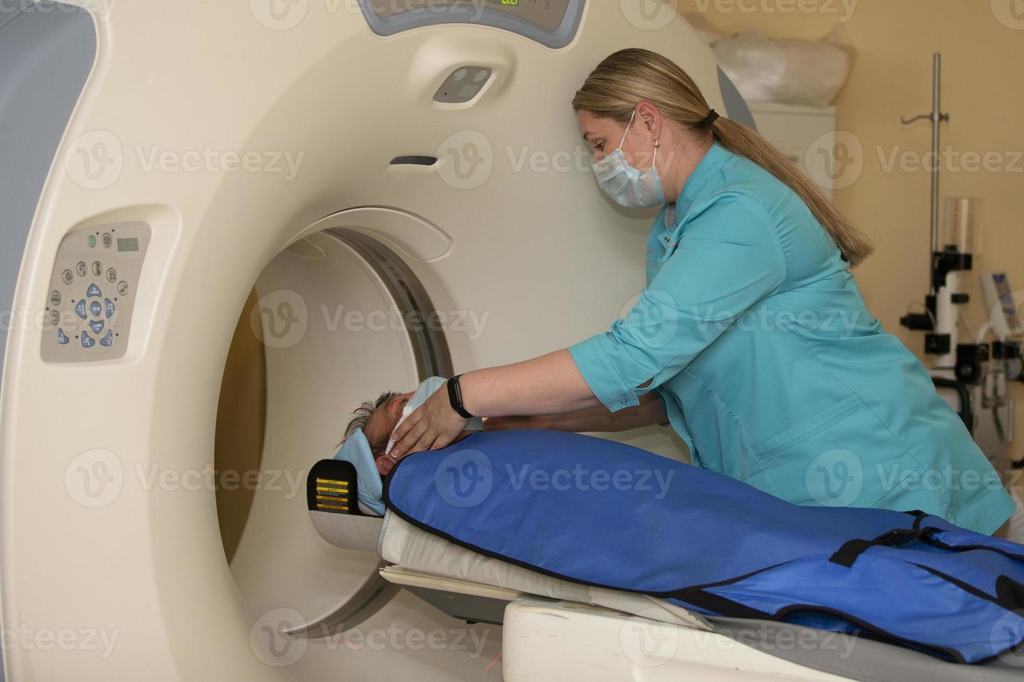 un médico en un médico vestido prepara un paciente para magnético resonancia imagen mri calculado tomografía en un hospital. foto