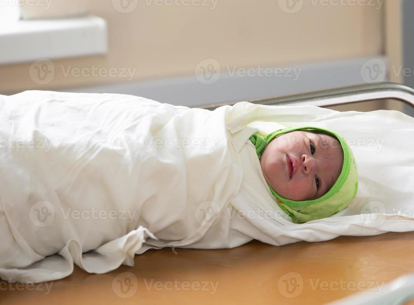 A newborn baby swaddled lies in the prenatal room. photo