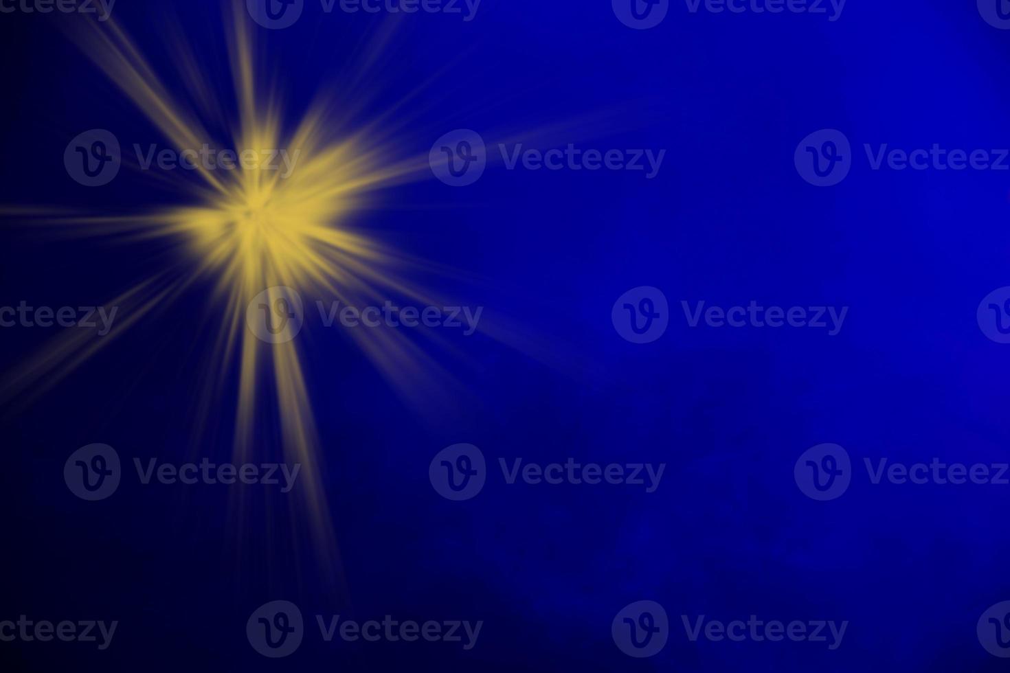 A yellow beam of light from a stage spotlight on a dark blue smoky background. Stage illumination. photo