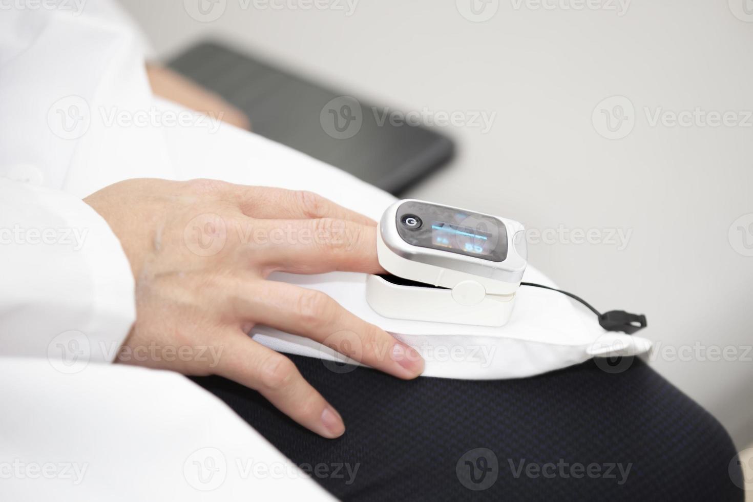 Close up of wrinkled hand of senior woman hospitalized with saline solution tube intravenous, iv drip. Detail of pulse oximeter on index to measure blood oxygen saturation in hospital. photo