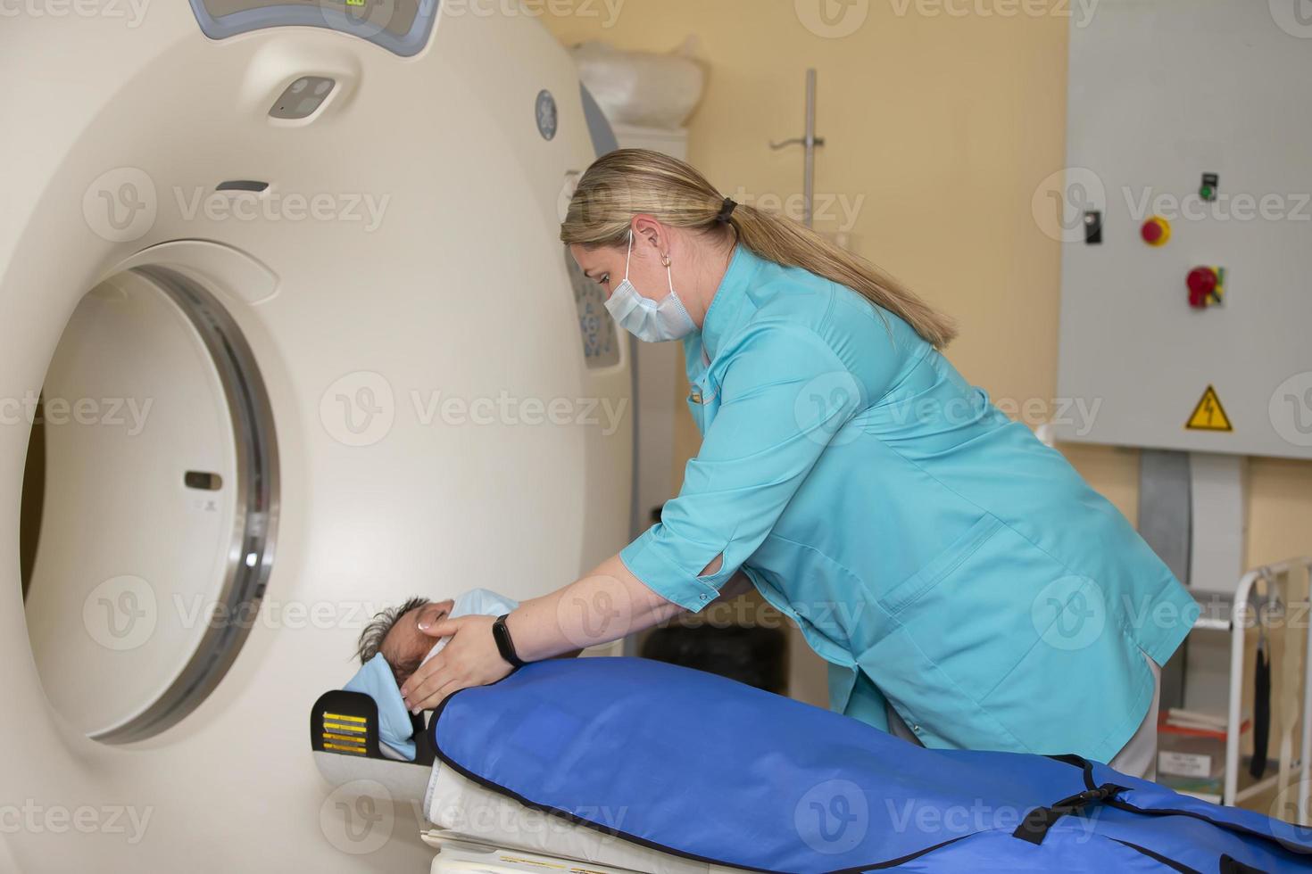 un médico en un médico vestido prepara un paciente para magnético resonancia imagen mri calculado tomografía en un hospital. foto