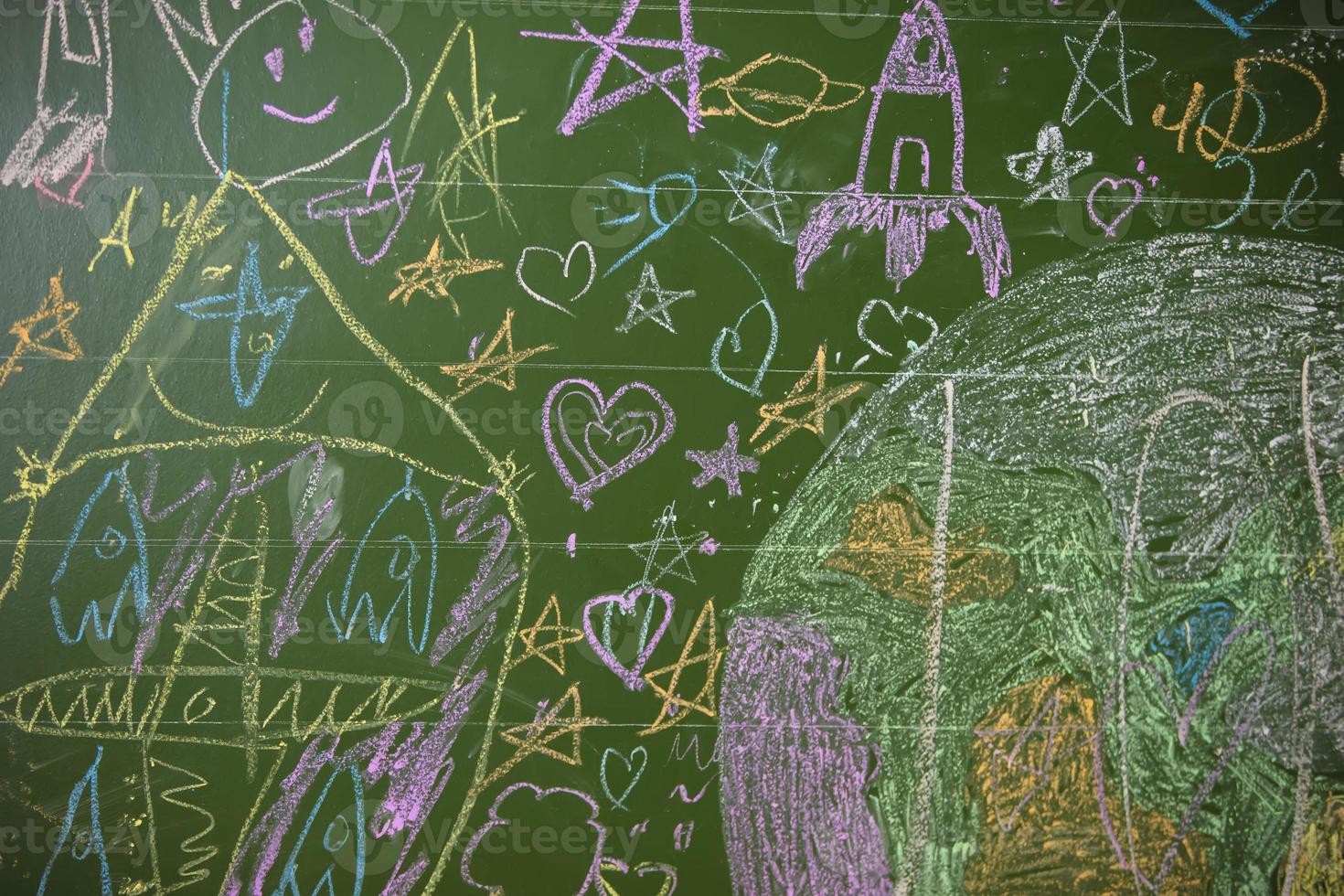 Drawings of children with chalk on a school green board. photo