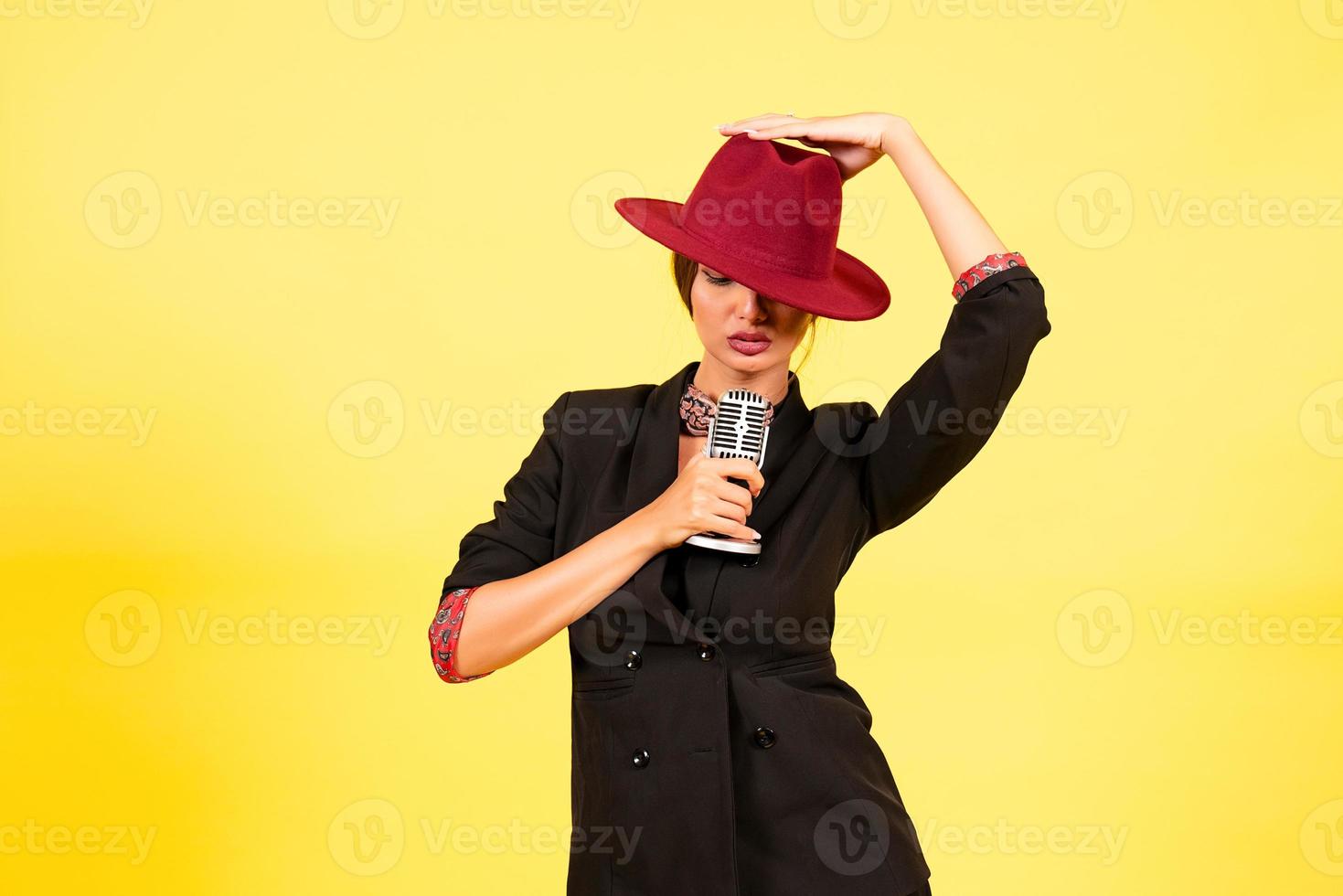 girl in a black suit on a yellow background sings in a retro microphone, portrait, music photo