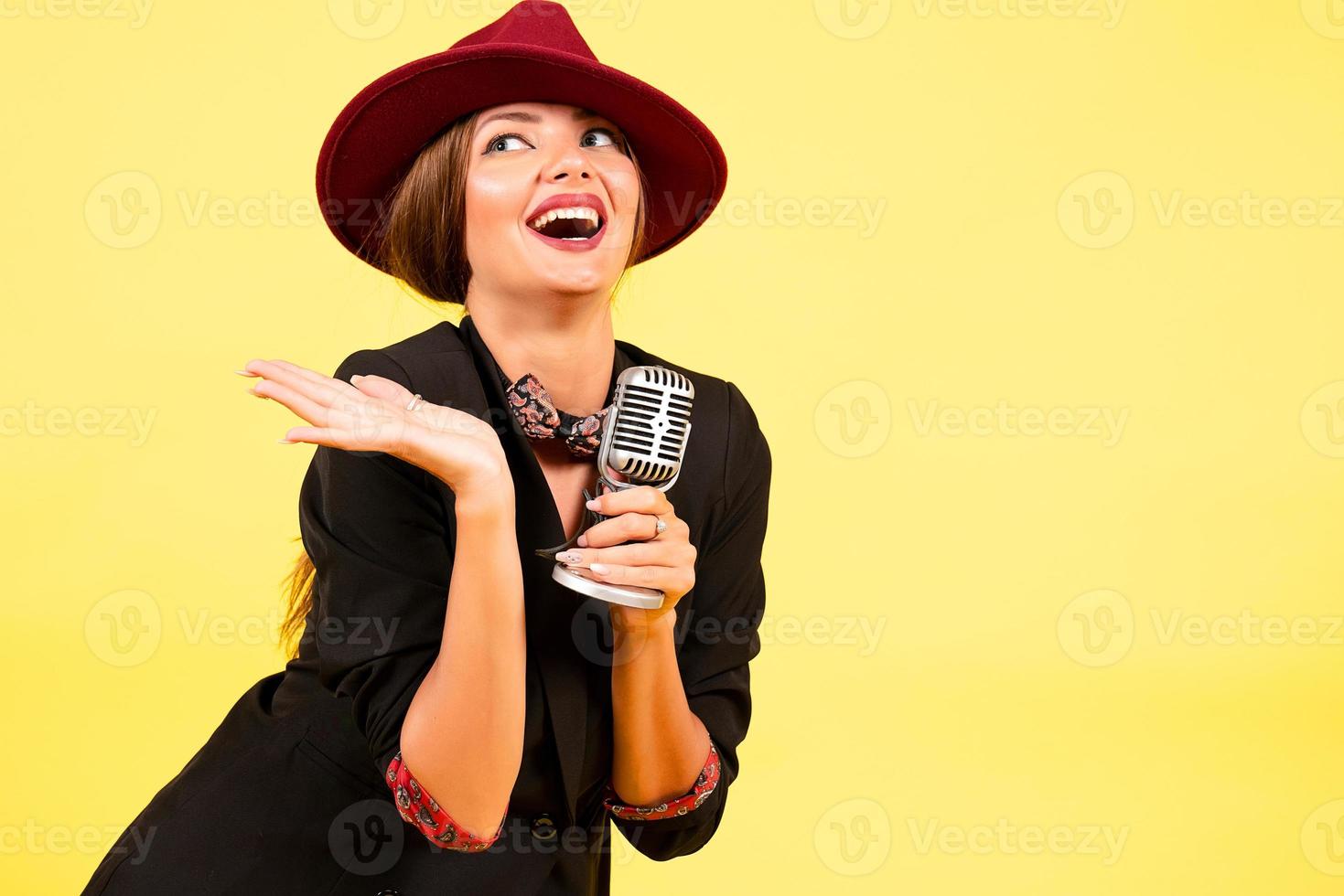 girl in a black suit on a yellow background sings in a retro microphone, portrait, music photo