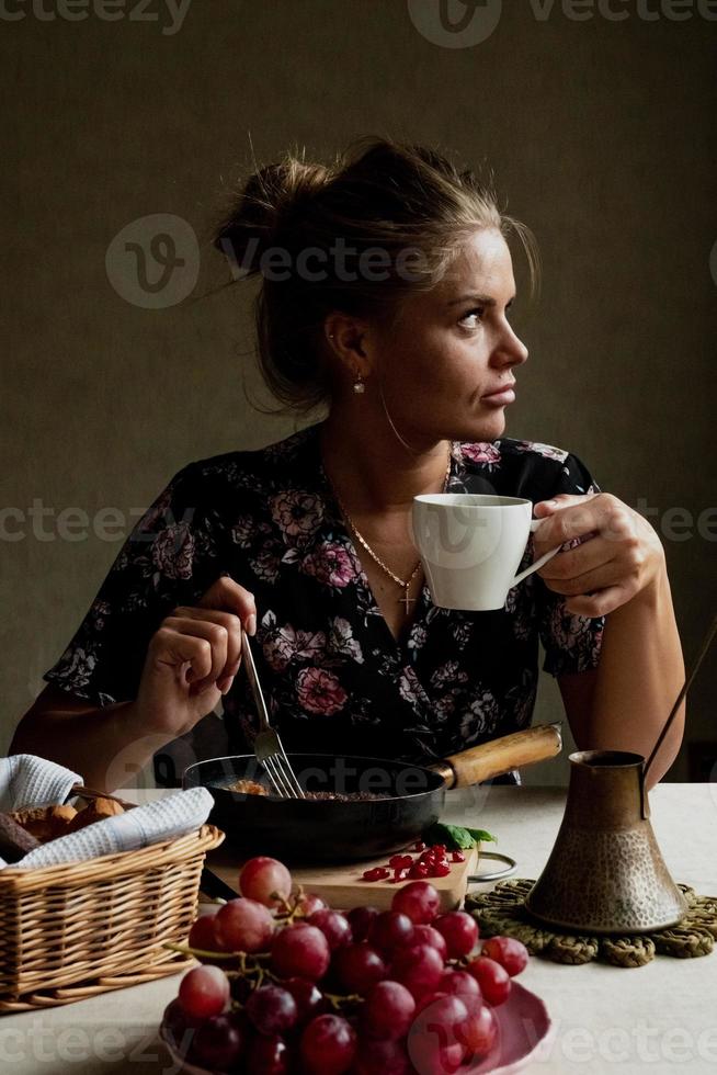 Girl having breakfast in the kitchen early in the morning photo