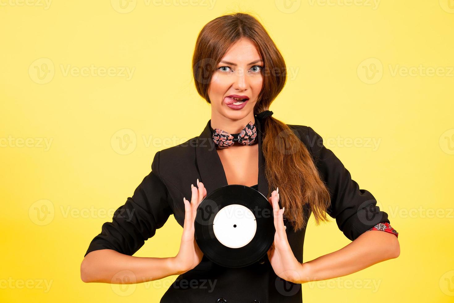 niña en un negro traje en un amarillo antecedentes con un grabar en su manos, música, el niña muestra emociones foto