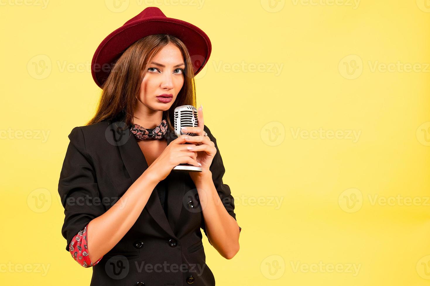 girl in a black suit on a yellow background sings in a retro microphone, portrait, music photo