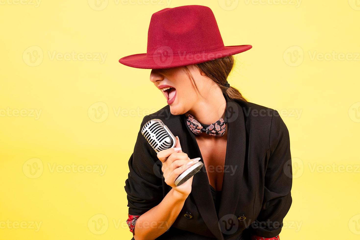 girl in a black suit on a yellow background sings in a retro microphone, portrait, music photo