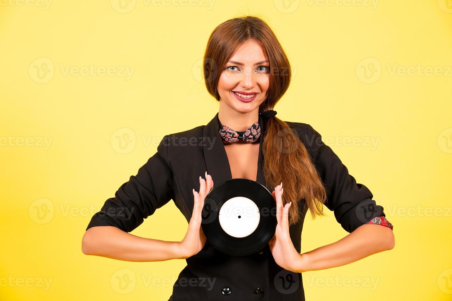 niña en un negro traje en un amarillo antecedentes con un grabar en su manos, música, el niña muestra emociones foto