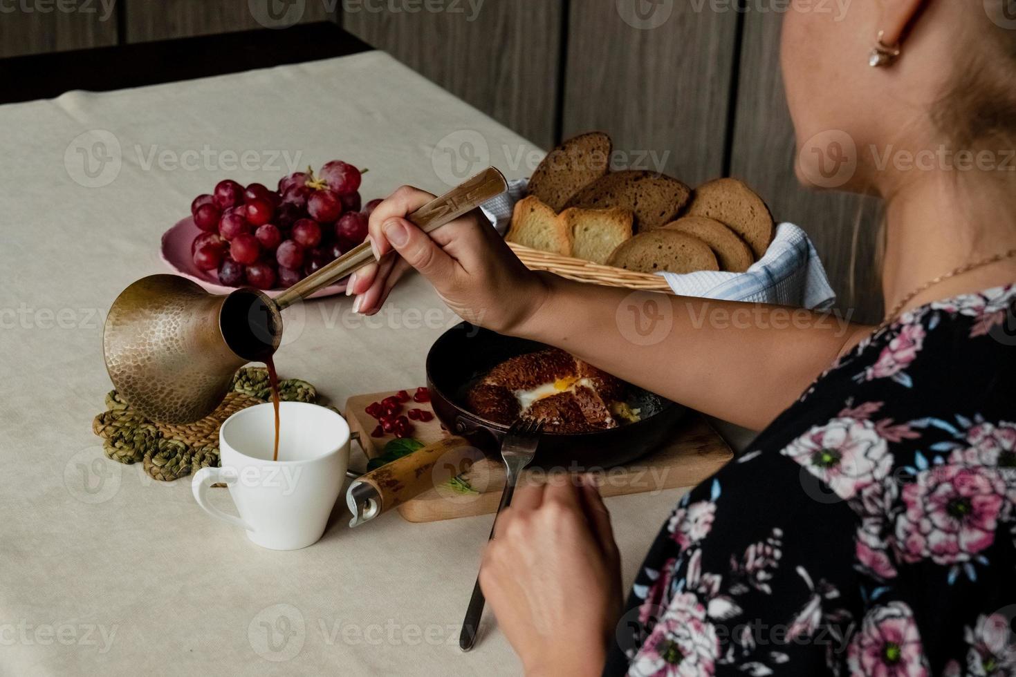 niña come desayuno y vierte café desde un turco foto