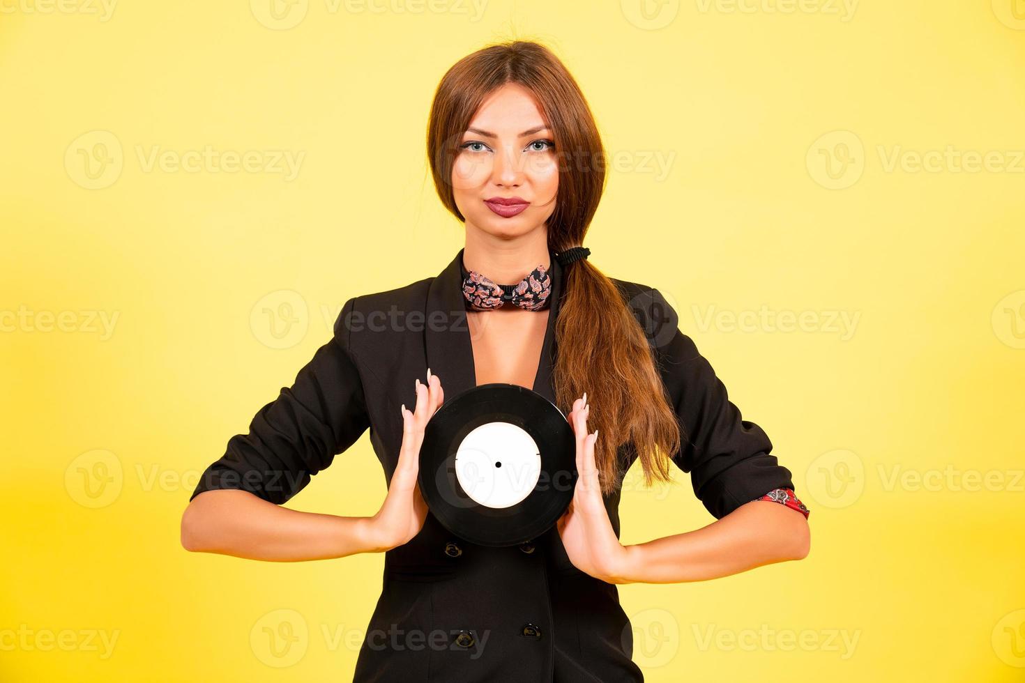 niña en un negro traje en un amarillo antecedentes con un grabar en su manos, música, el niña muestra emociones foto