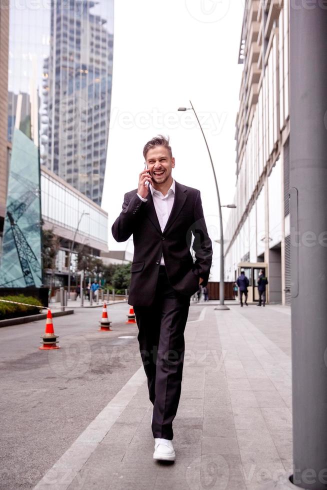 guy in a suit talks on the phone laughs and walks photo