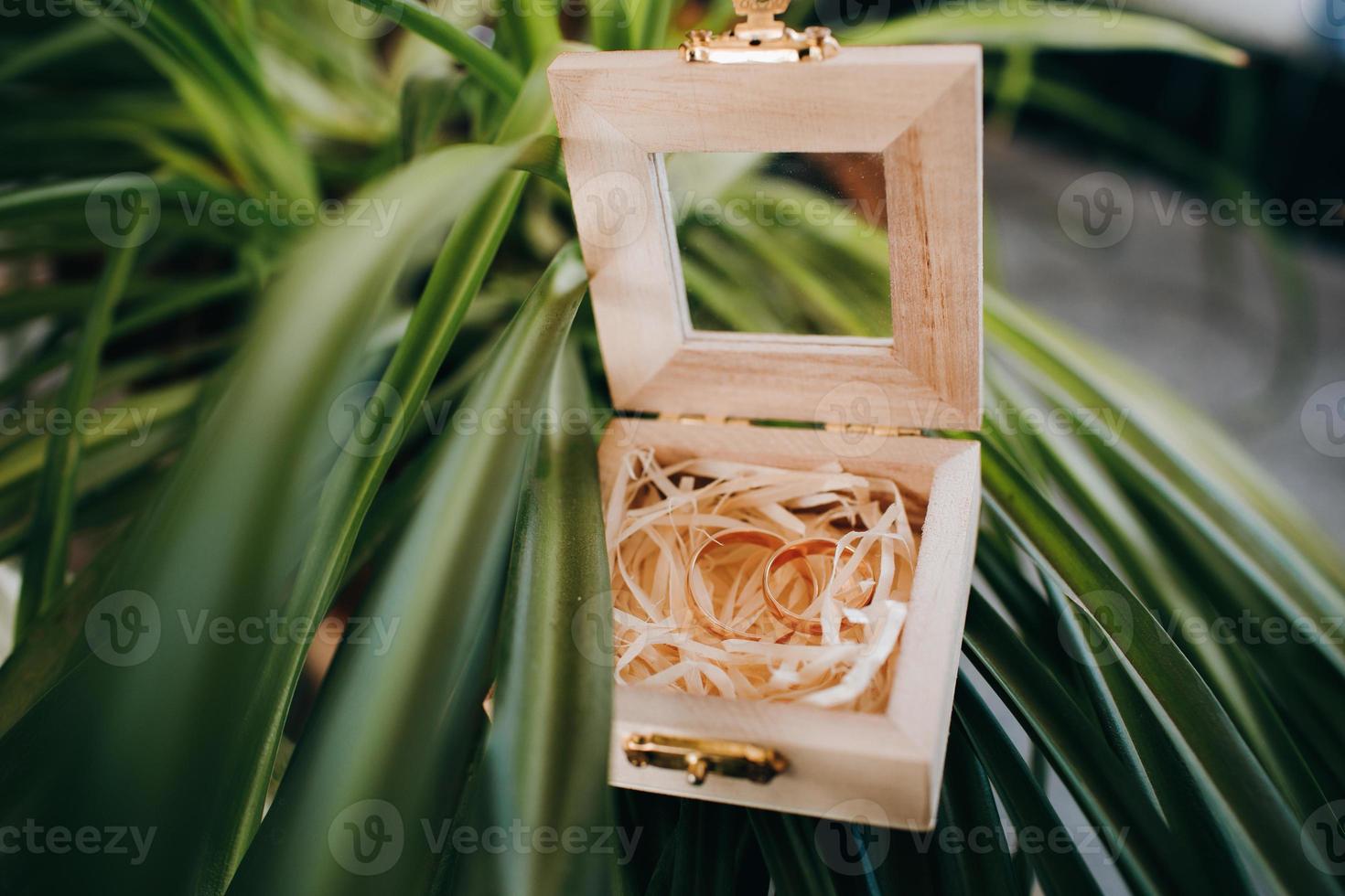 wedding gold rings in a wooden box on the green grass. wedding accessories for the ceremony. photo