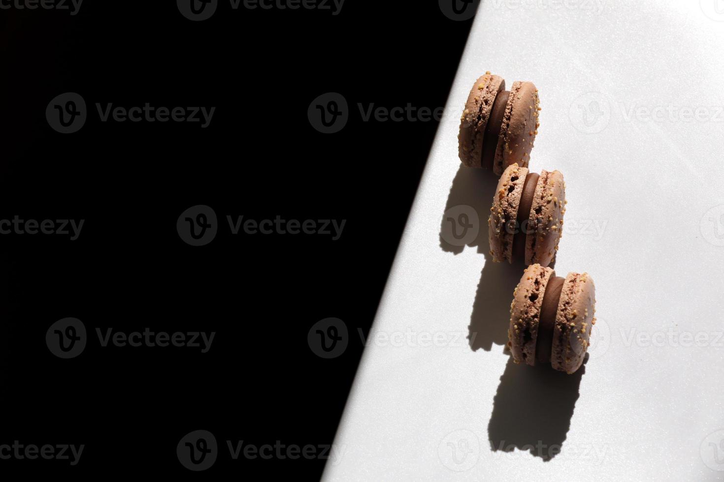 Sweet brown chocolate french macaroons or macarons dessert isolated on white background with light rays from window. copy space. photo