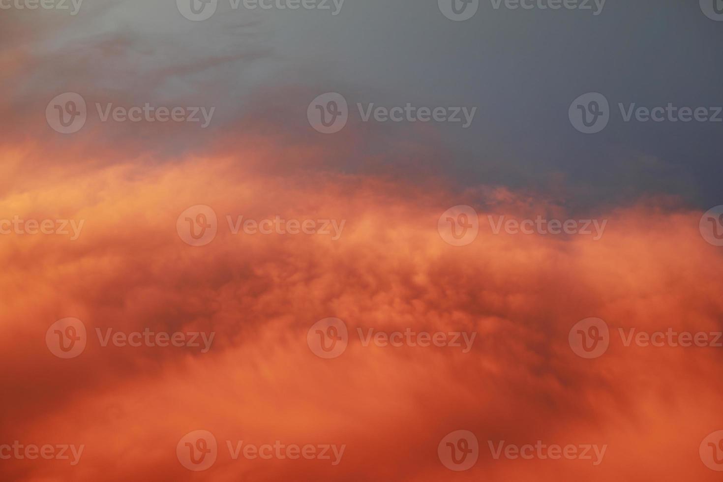 Dramatic sunset landscape with puffy clouds lit by orange setting sun and blue sky. photo