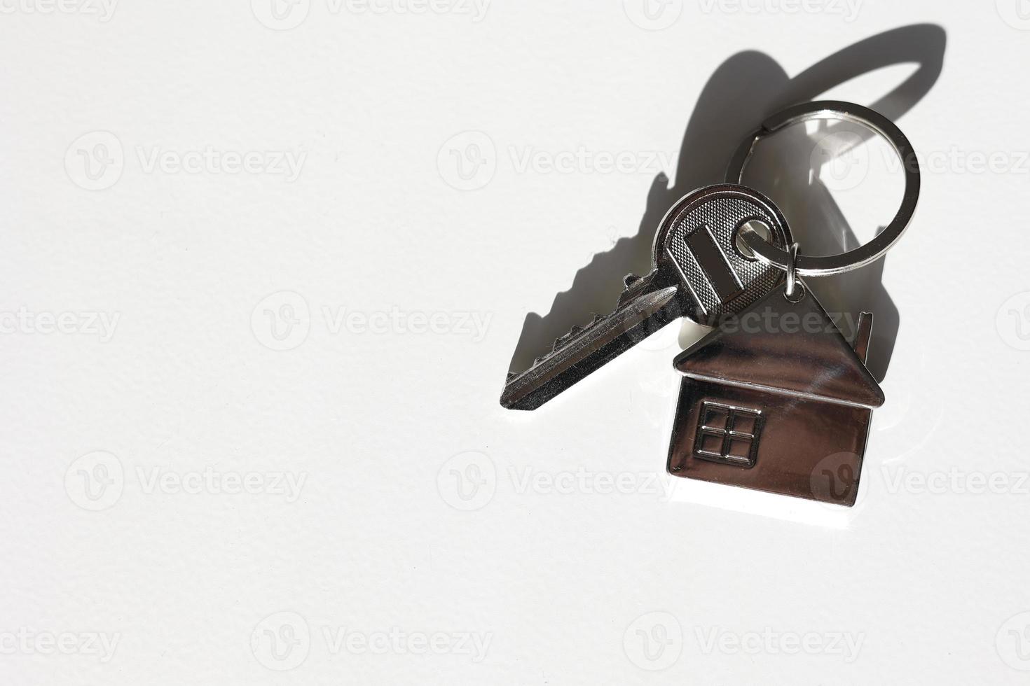 Key and metal house shaped keychain arrangement on white background with shadow. Business and insurance. concept of buying, selling, renting real estate, mortgages, your own home. Place for text. photo