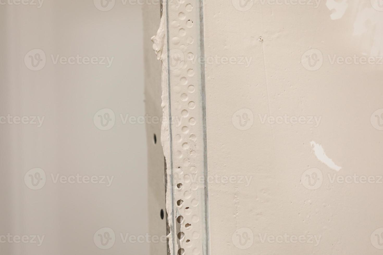 The worker set the metal wall profile in the new flat. Plasterboard metal profiles. Gypsum board installation background. Metallic material for building walls photo