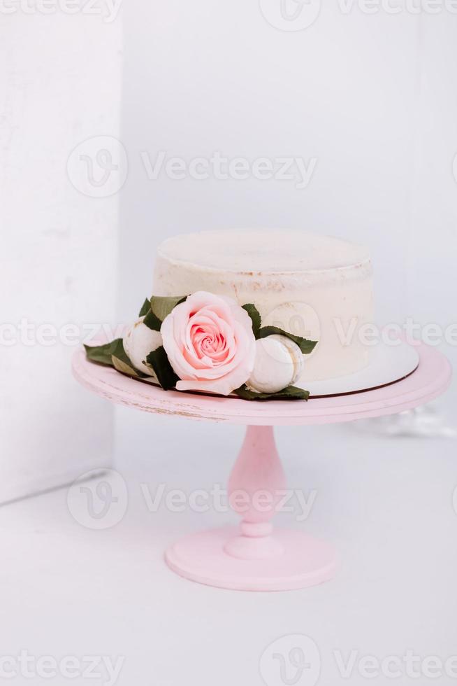 Beautiful white cream cake decorated with 2 year old candle and roses in white studio. Birthday party - Concept of a year of birth, party, celebration of life and memorable moments. photo