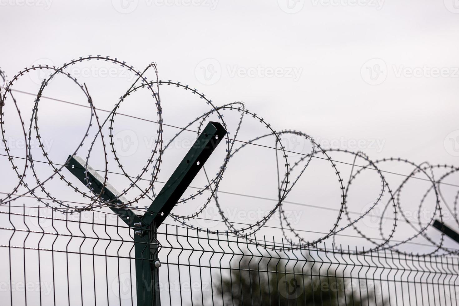 fence of barbed metal wire against the background of clouds, the concept of freedom, unfreedom, close up. photo