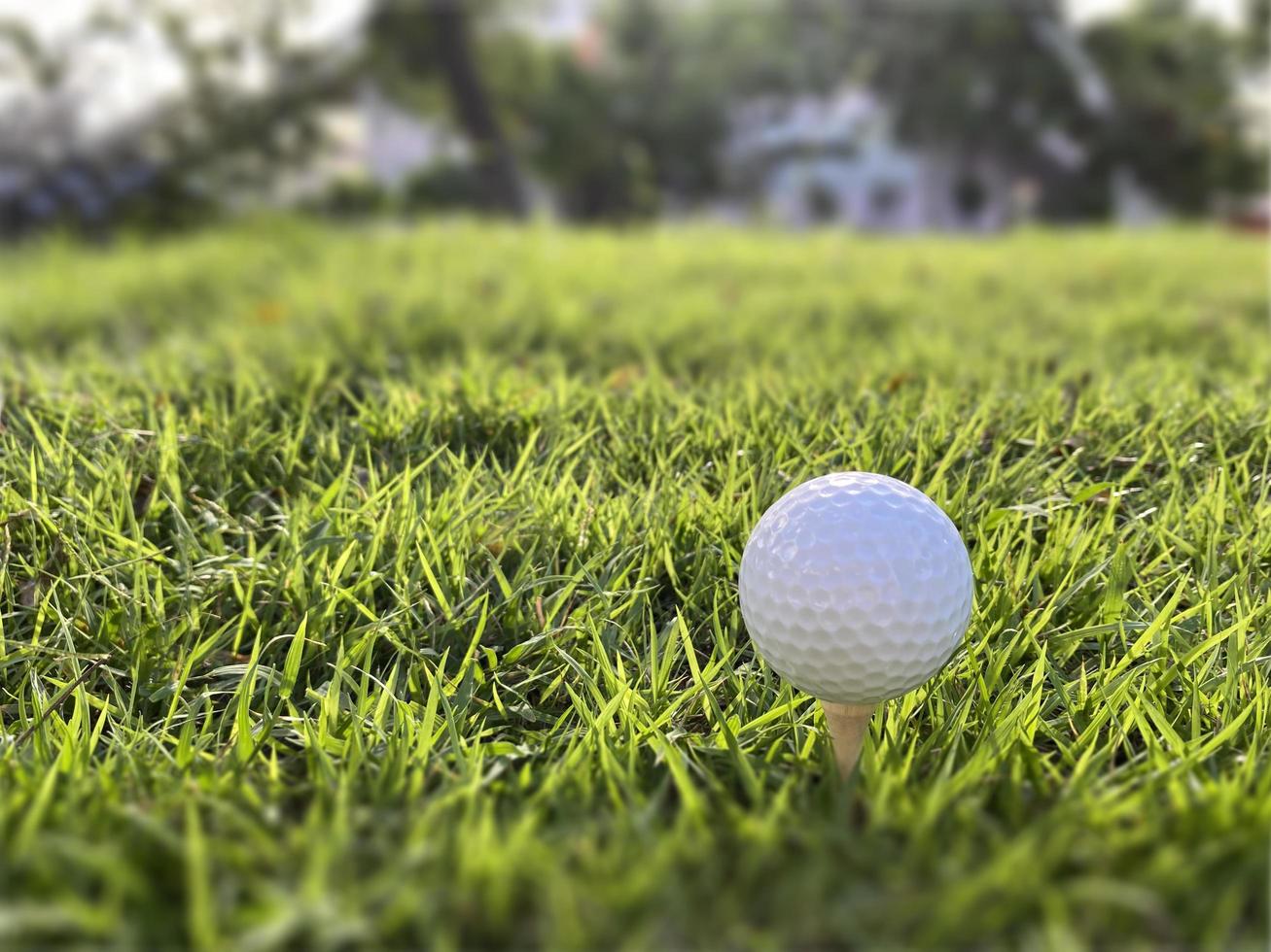 pelota de golf cerca de la hierba verde en el hermoso paisaje borroso del campo de golf con amanecer, atardecer en segundo plano. concepto de deporte internacional que se basa en habilidades de precisión para la relajación de la salud. foto