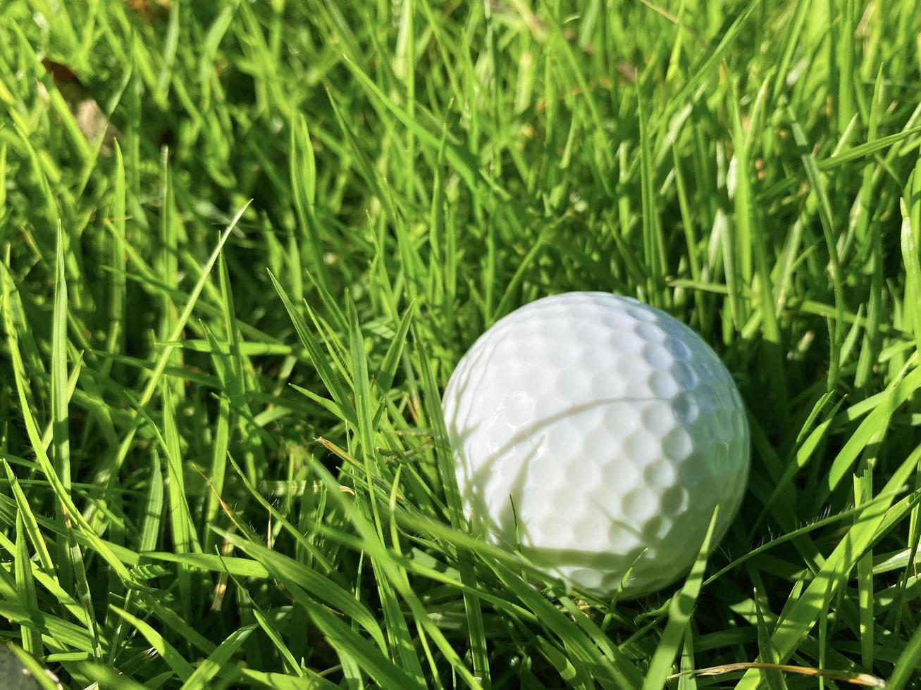 Golf ball close up on green grass on blurred beautiful landscape of golf course with sunrise,sunset time on background.Concept international sport that rely on precision skills for health relaxation. photo