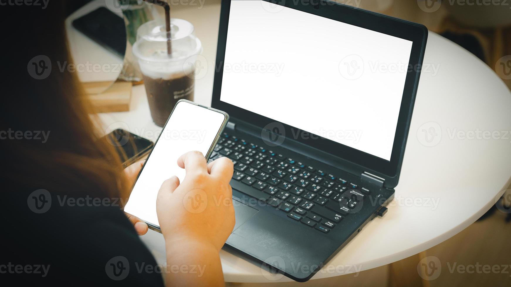 mujer sentado y trabajando con un cuaderno computadora y utilizar un móvil teléfono negocio mujer concepto a lo largo con el teléfono pantalla recorte camino y el cuaderno pantalla foto