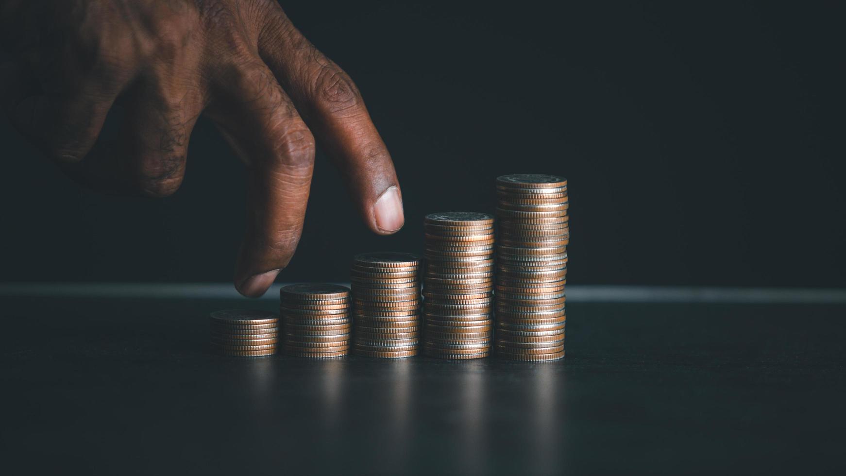 Hand walking on a pile of coins with black background. Business ideas concept. photo