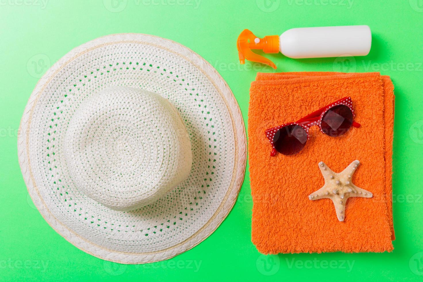 Summer beach flat lay accessories. Sunscreen bottle cream, towel and seashells on colored Background. Travel holiday concept with copy space photo