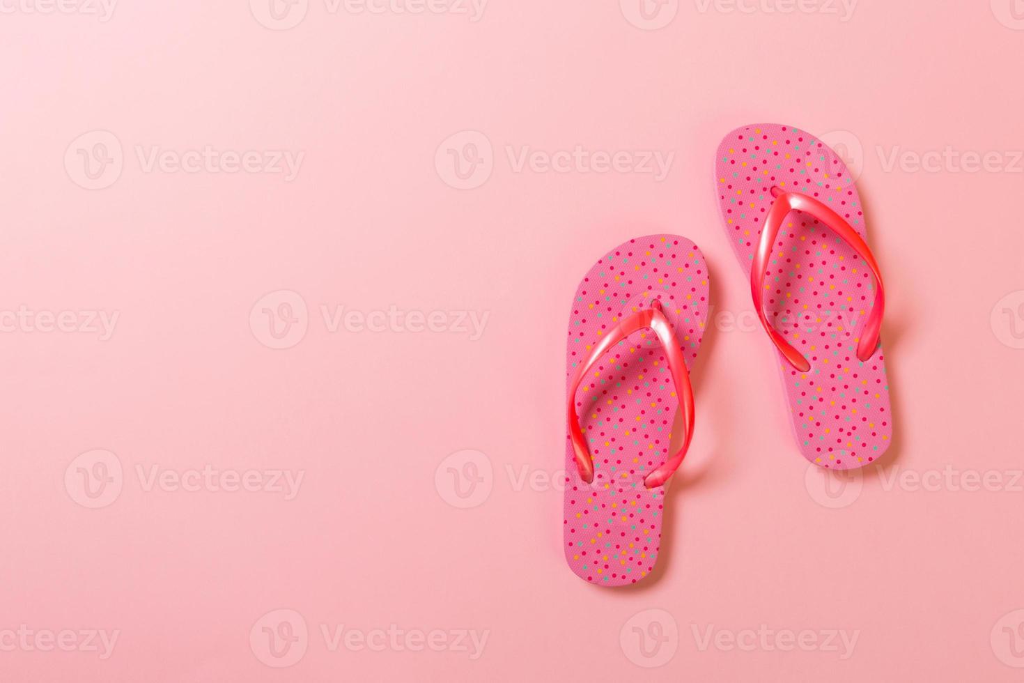 Coral flip flops on pink Background. Top view with copy space photo