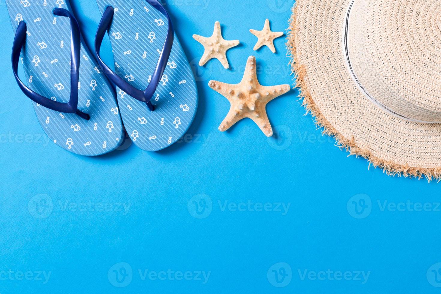 Summer beach flat lay accessories. Sunscreen straw hat, flip flops and seashells on colored Background. Travel holiday concept with copy space photo
