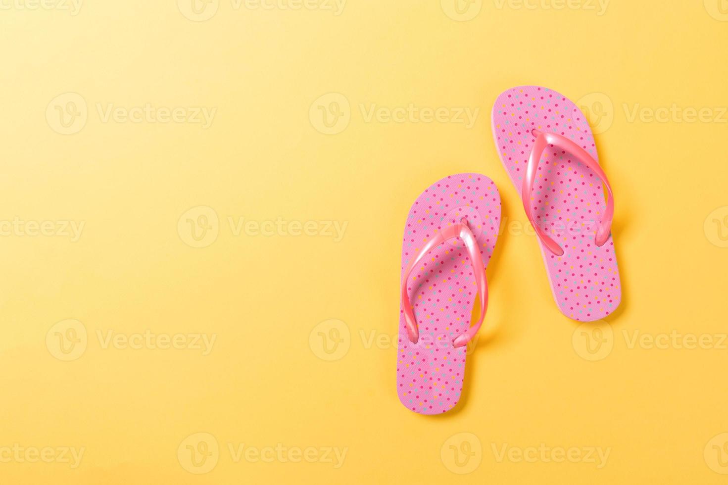 Pink flip flops on yelow Background. Top view with copy space photo
