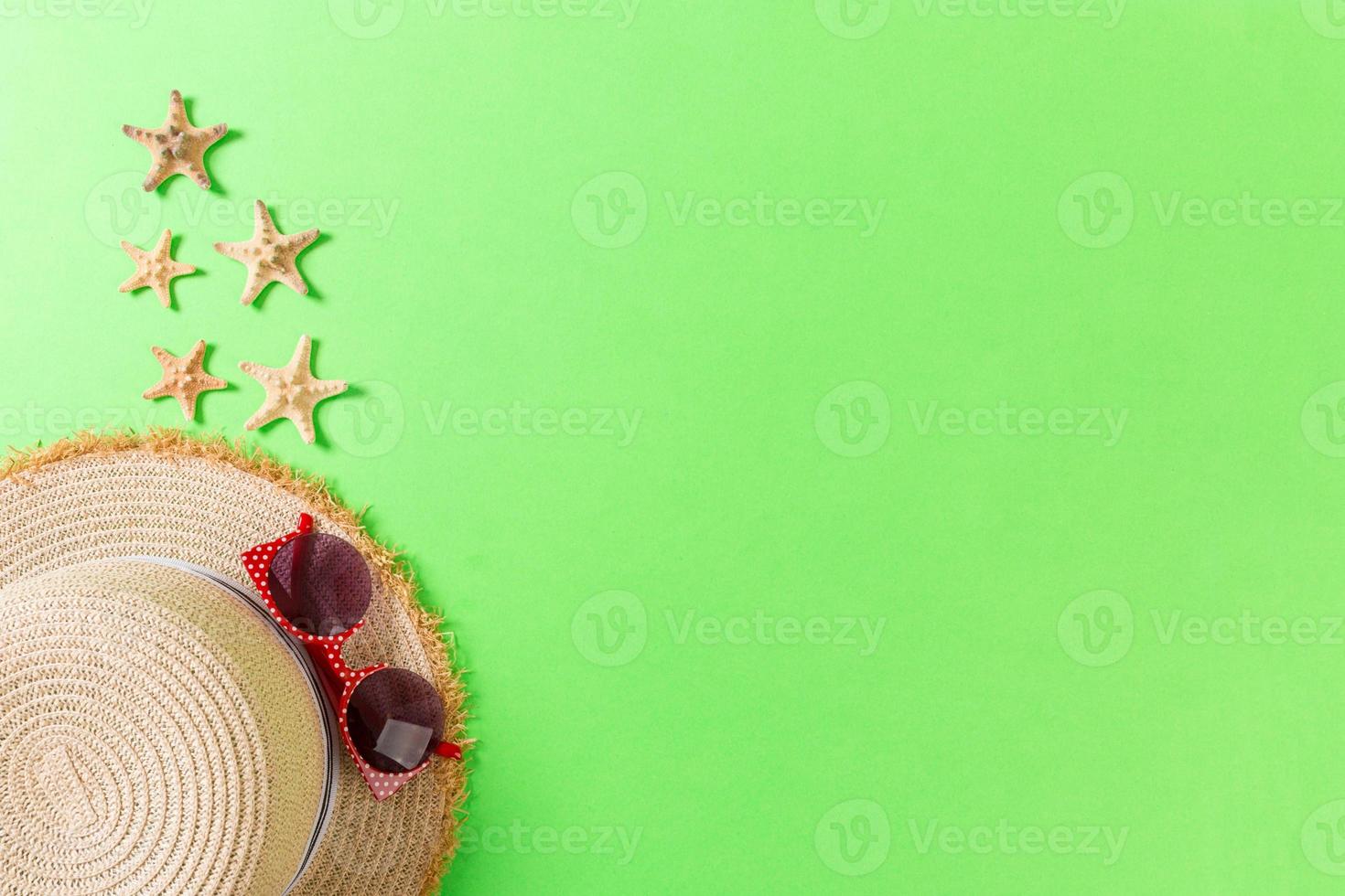 Summer holiday background with straw hat and seashells on green background top view with copy space photo