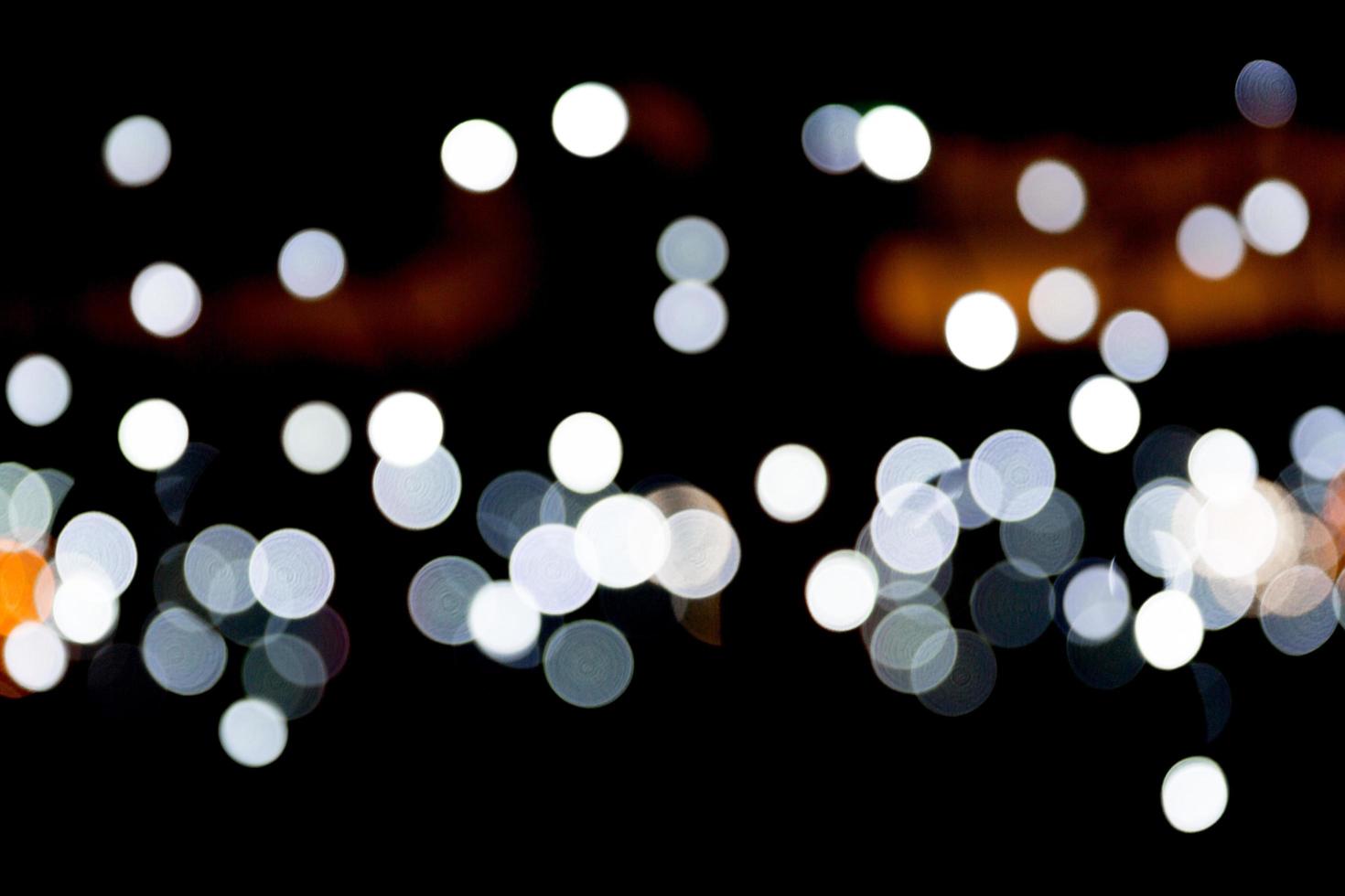 Bokeh abstracto de luces de la ciudad blanca sobre fondo negro. desenfocado y borroso muchas luces redondas foto