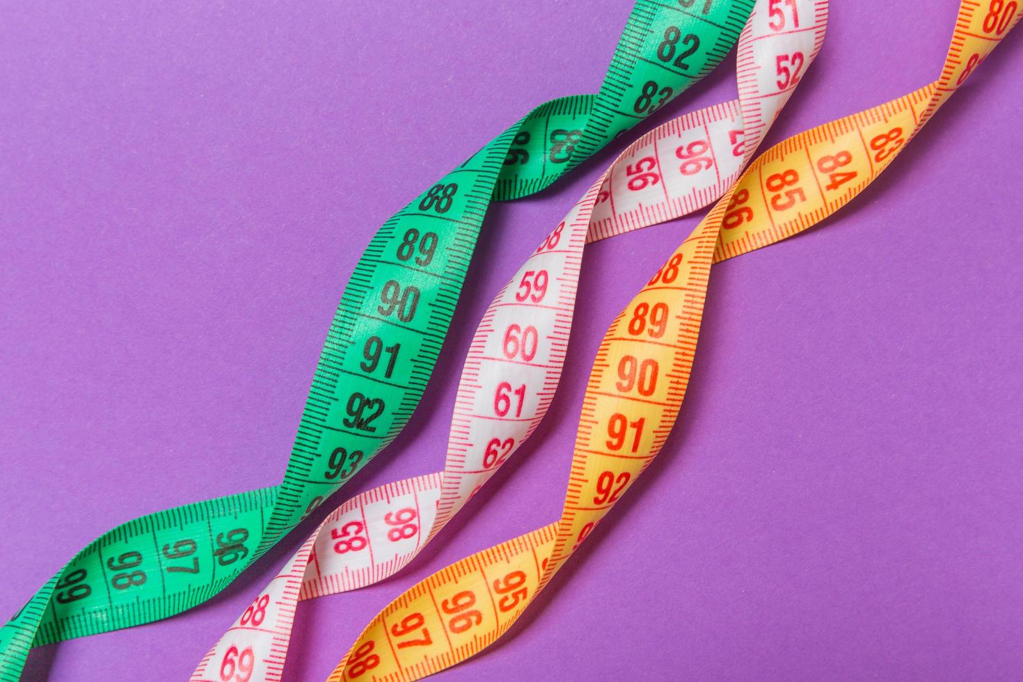 Perspective view of spiral colorful measure tapes on purple background. Concept of perfect female figure with empty space for your idea photo