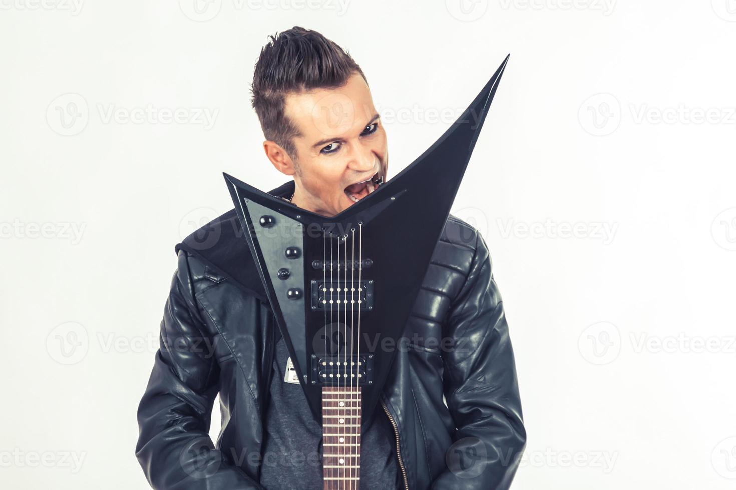 Portrait of musician biting his electric guitar. photo