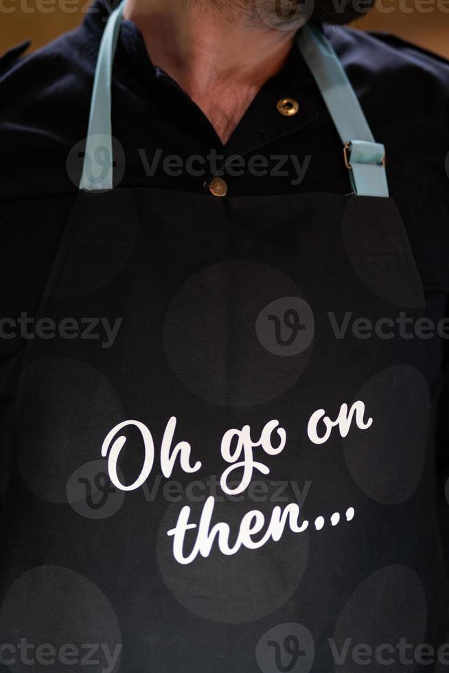 barista, waiter with beard close-up black  apron with inscription. photo