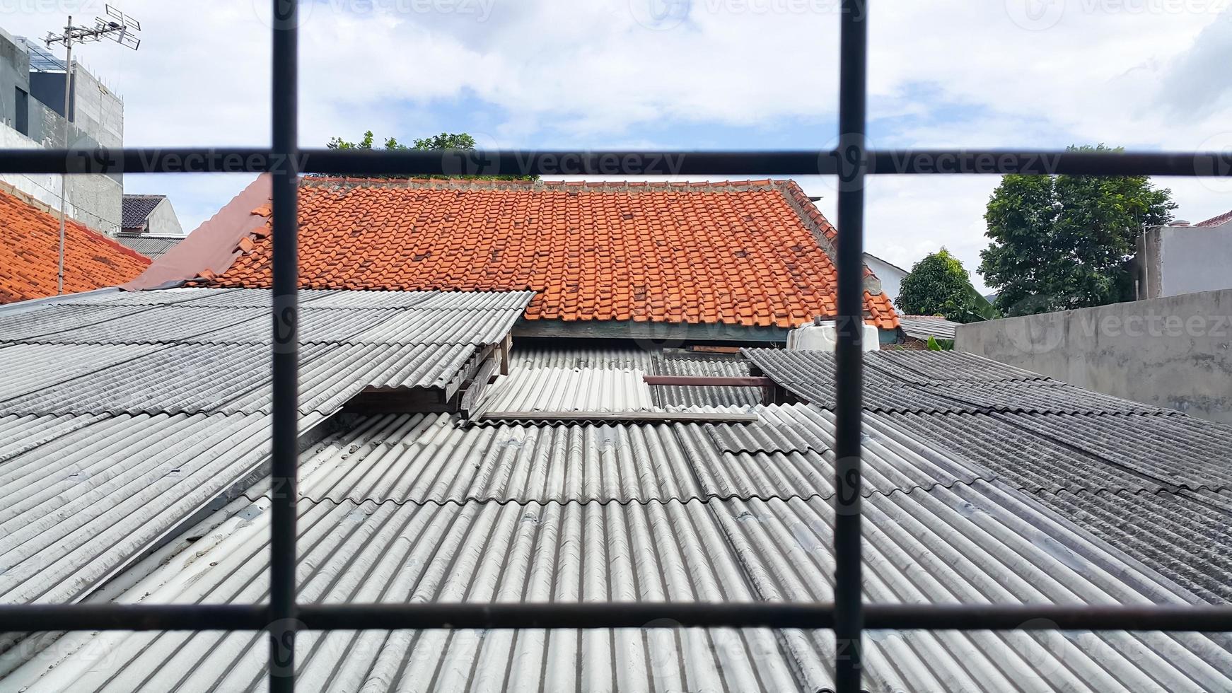 View of the roof of the old house and the blue sky. Seen from behind an iron trellis. Selective focus. photo