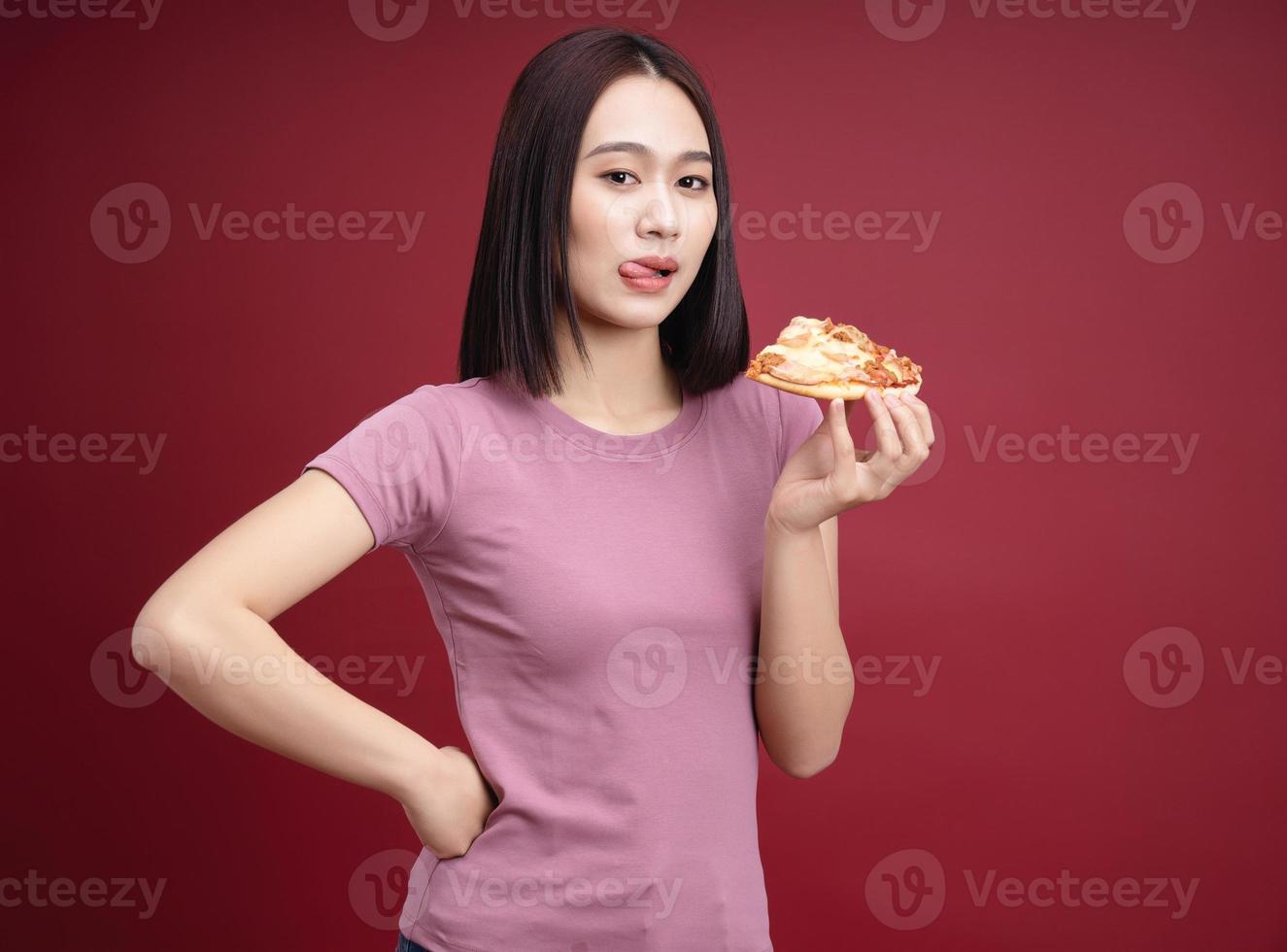 Young Asian woman eating pizza on background photo