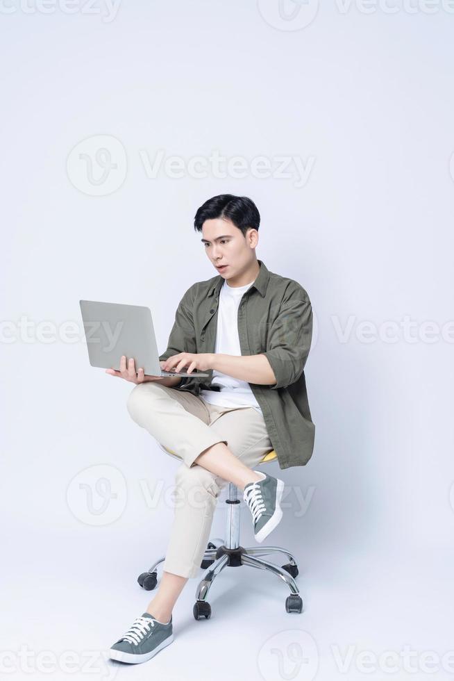 Young Asian business man sitting on chair and using laptop on background photo