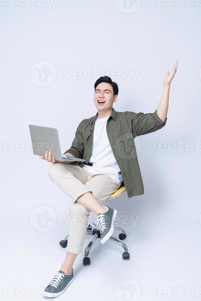 Young Asian business man sitting on chair and using laptop on background photo