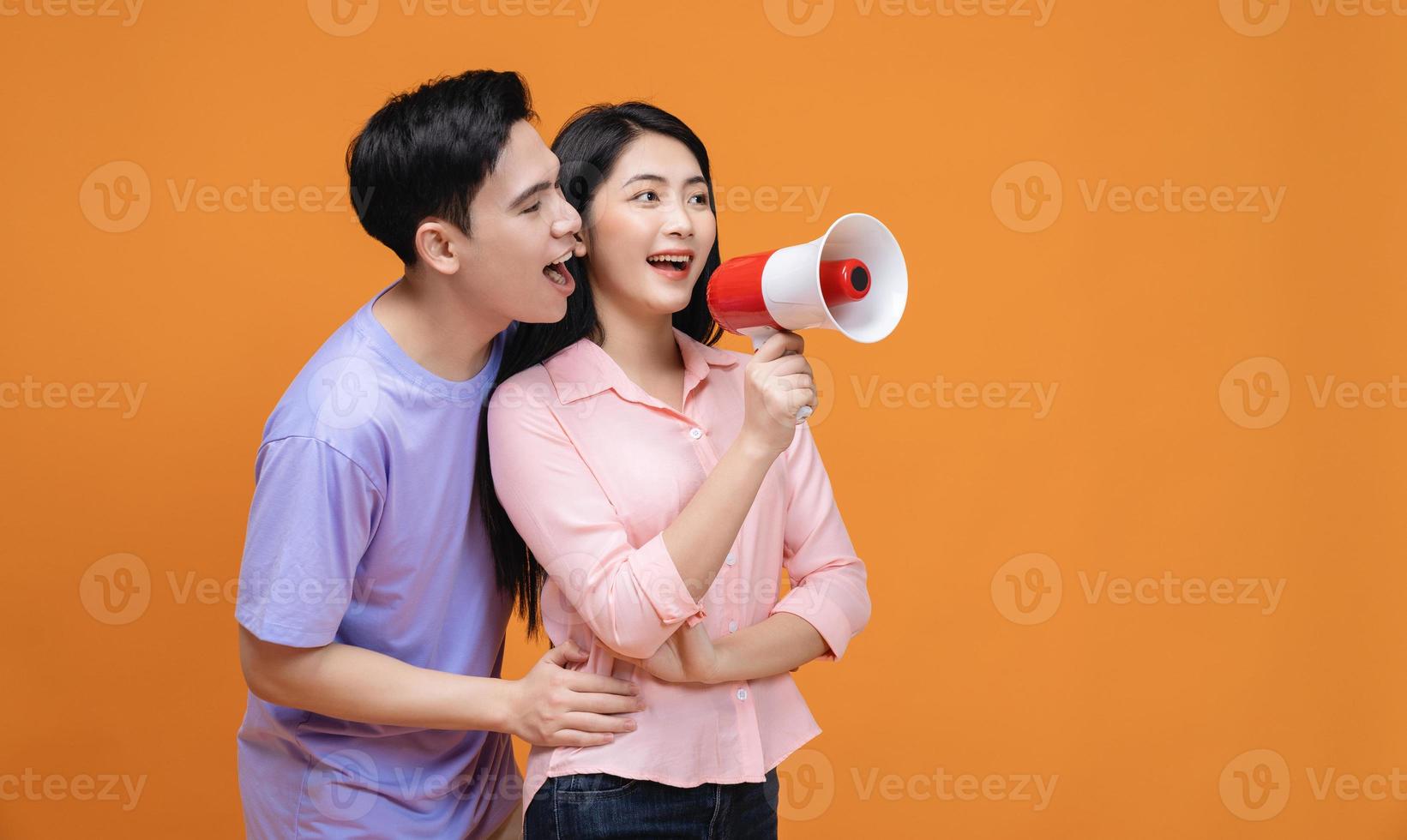 Young Asian couple with megaphone on background photo