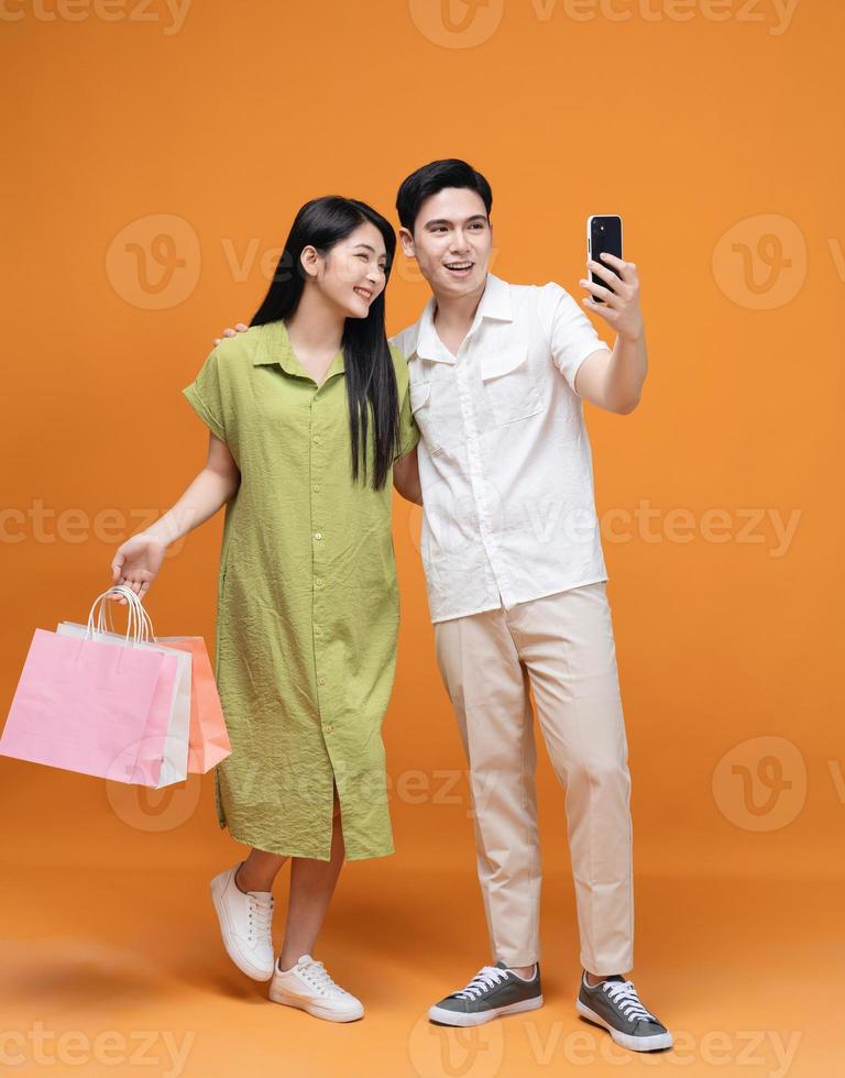 Young Asian couple holding shopping bag on background photo