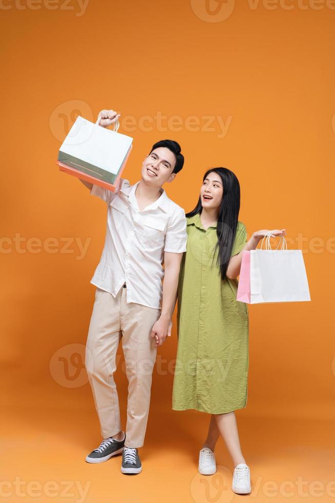 Young Asian couple holding shopping bag on background photo