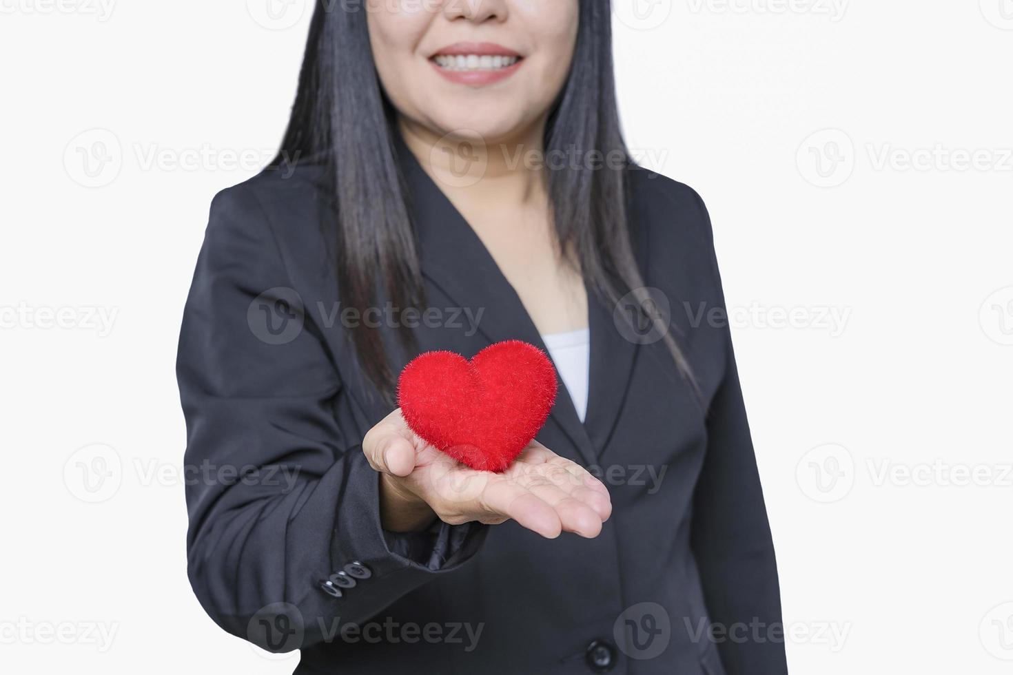 Happy woman Holding a Heart Shape Paper. presenting to Camera. Love, Health Care, Donation and Charity Concept. Close-up of smiling volunteer or businesswoman. photo