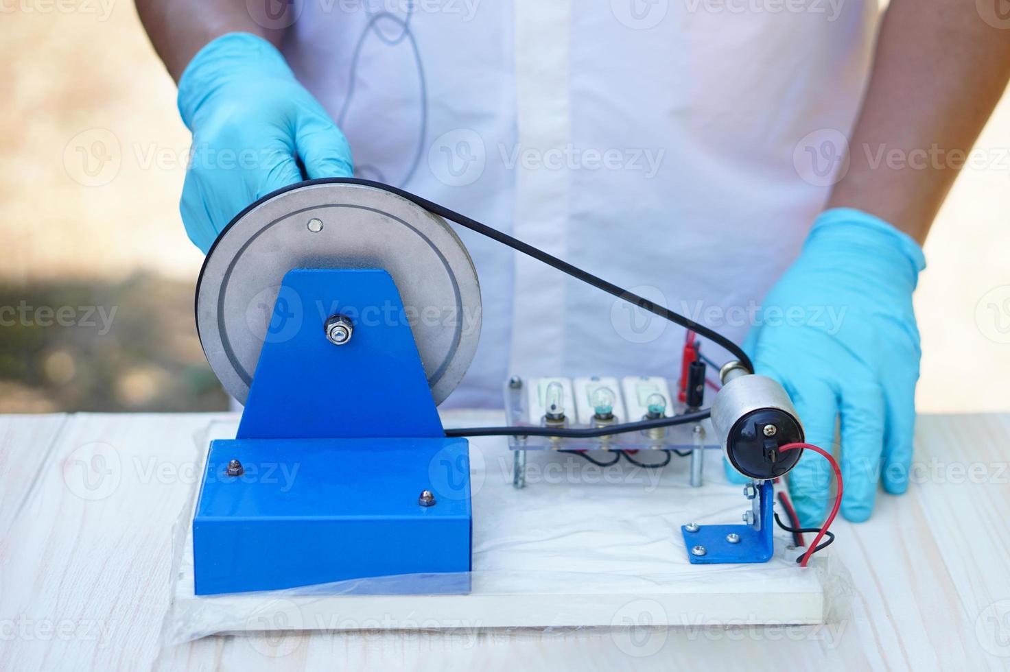 Close Up hands wear blue gloves demonstrate science experiment about electricity circuit from dynamo kit for teaching. Concept, science subject, project work. Experiment, education. Outdoor class. photo