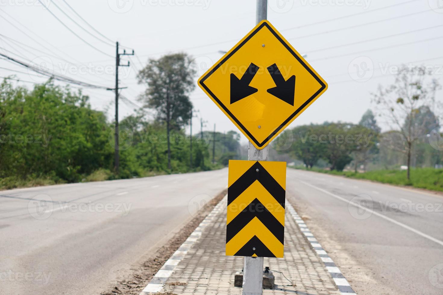 Yellow warning road sign with symbol of arrows on the road  for the two way run  in rural of Thailand. Concept , Warning traffic sign for transportation. photo