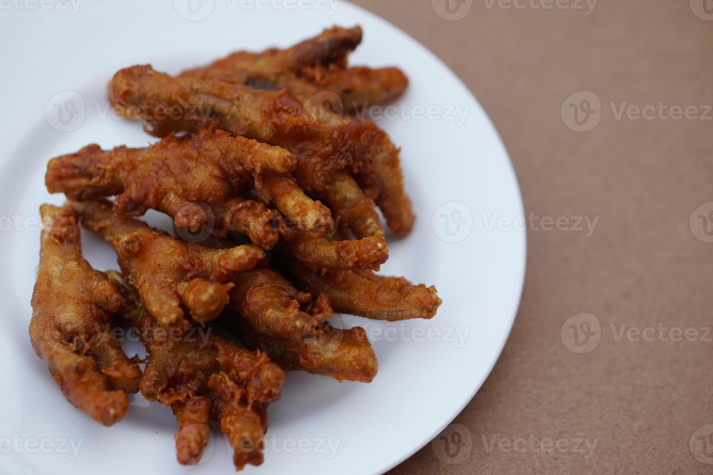 Closeup crispy fried checken feet on white plate. Concept, weird, exotic food. delicious and popular street food in Thailand photo